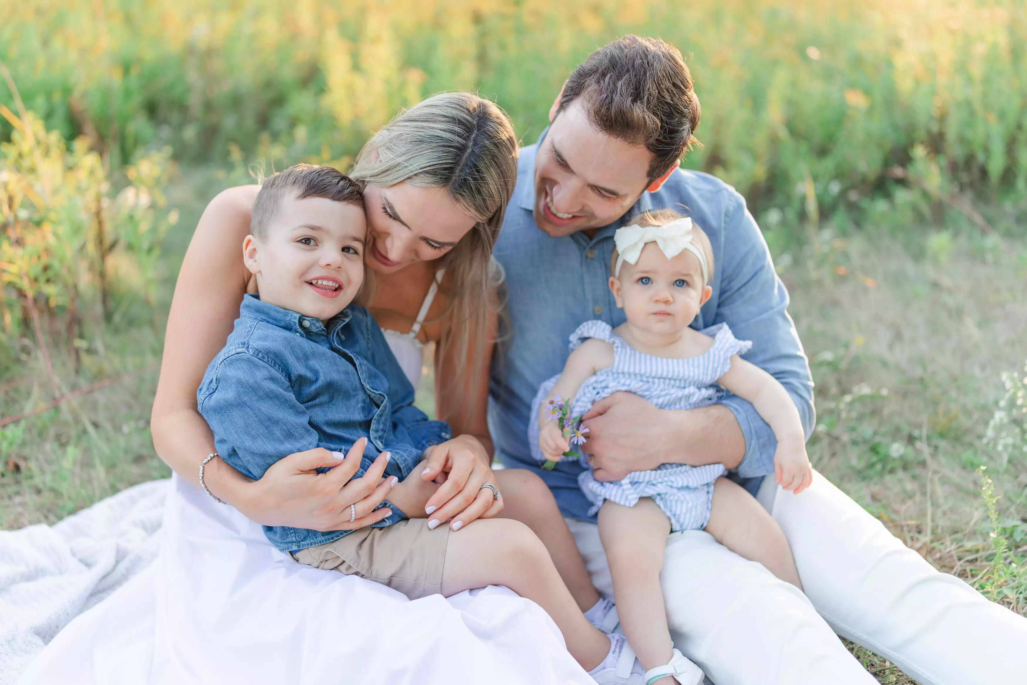 Family sitting together on a blanket in a field during golden hour in Hamilton Ontario.